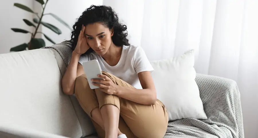 mujer mirando el móvil con gesto triste y apático