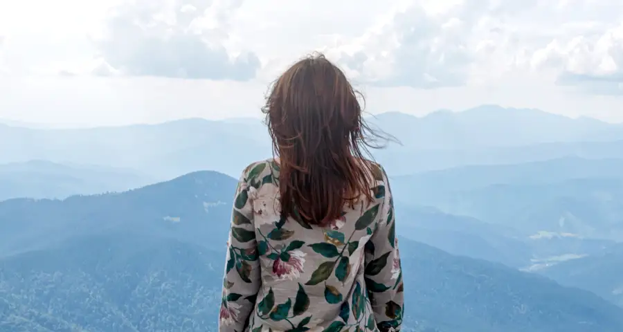 mujer observando montañas en paisaje natural